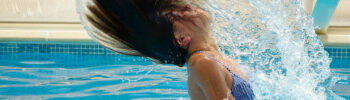 Eine Frau im Schwimmbad schüttelt ihre nassen Haare